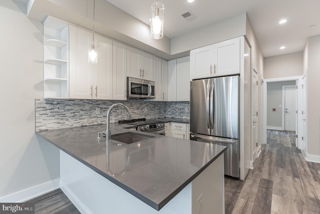 kitchen with kitchen peninsula, appliances with stainless steel finishes, wood-type flooring, and white cabinets