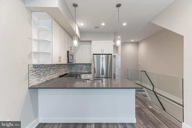 kitchen with dark hardwood / wood-style floors, stainless steel appliances, kitchen peninsula, and white cabinetry