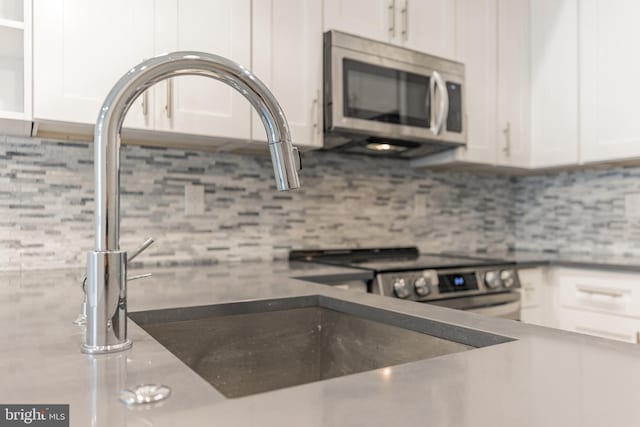 kitchen with range, tasteful backsplash, and white cabinetry