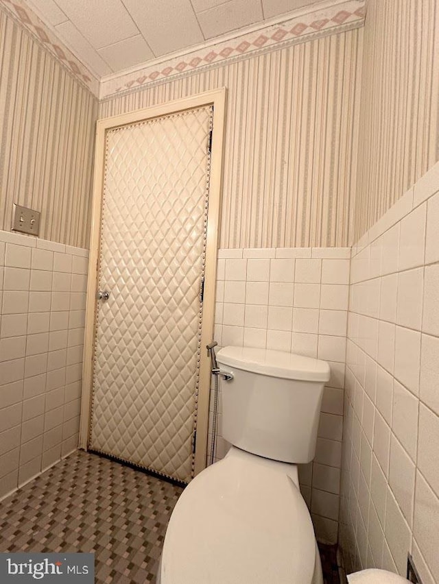 bathroom with toilet, tile flooring, and tile walls