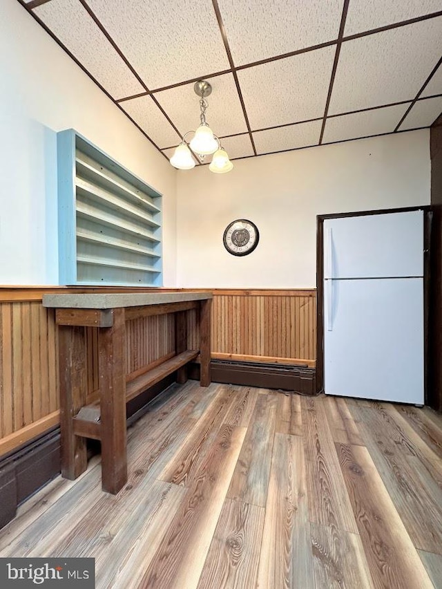 interior space with a drop ceiling and hardwood / wood-style floors