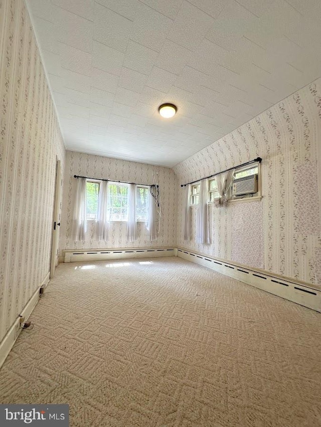 spare room featuring a wall unit AC, carpet, and a baseboard radiator