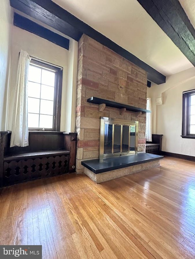 unfurnished living room with hardwood / wood-style floors, beamed ceiling, and plenty of natural light