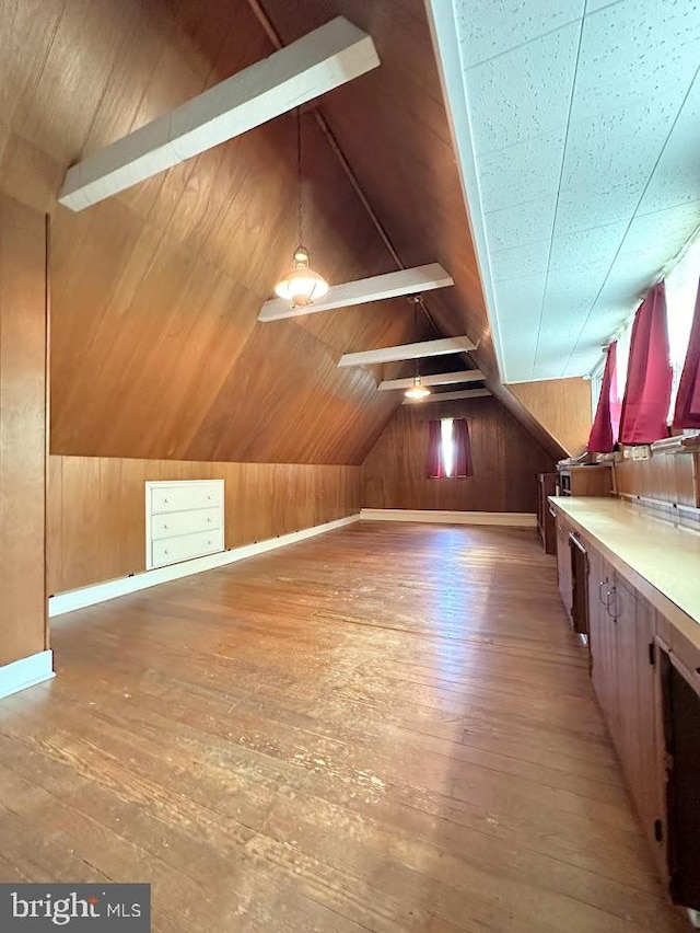 additional living space featuring wood-type flooring, lofted ceiling, and wood walls