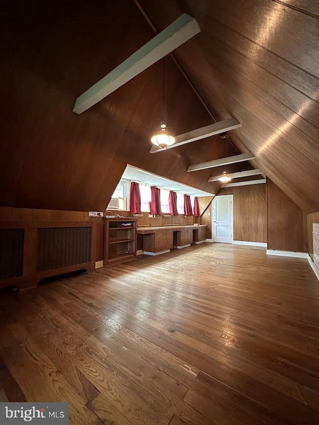 additional living space with wood-type flooring, vaulted ceiling, and wooden walls