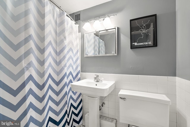 bathroom featuring tile walls and toilet