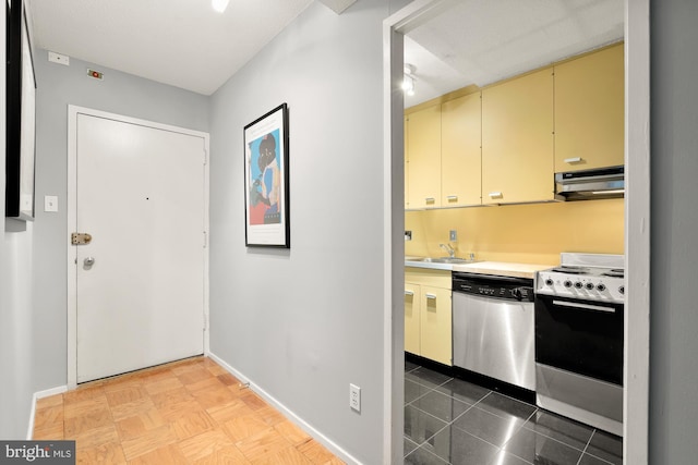 kitchen with exhaust hood, appliances with stainless steel finishes, tile flooring, cream cabinetry, and sink