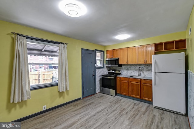 kitchen featuring tasteful backsplash, appliances with stainless steel finishes, light hardwood / wood-style flooring, and sink