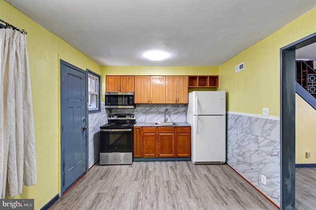 kitchen with tasteful backsplash, light hardwood / wood-style floors, stainless steel appliances, and sink