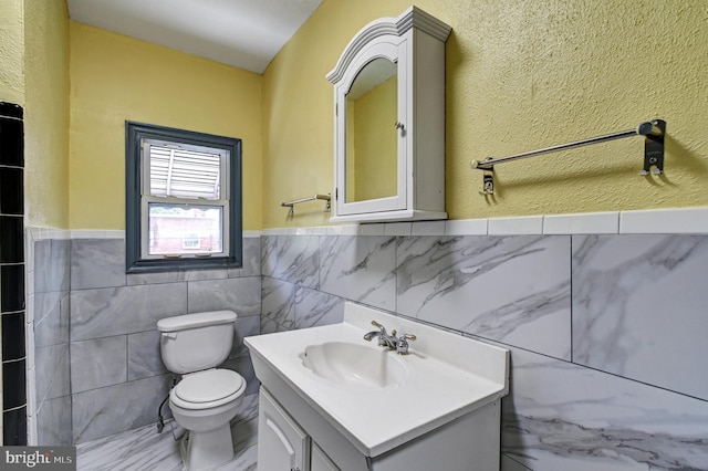 bathroom with tile flooring, tile walls, toilet, and large vanity