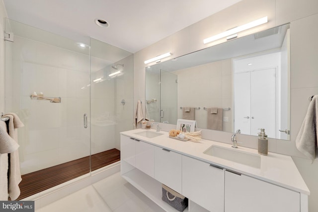 bathroom featuring tile floors, dual vanity, and walk in shower