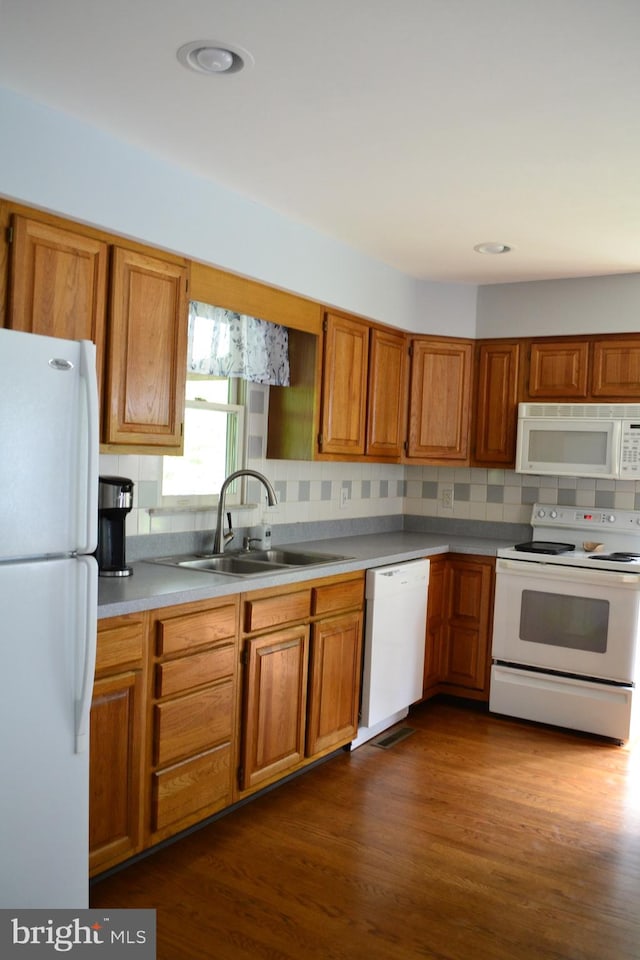 kitchen featuring sink, tasteful backsplash, white appliances, and dark wood-type flooring