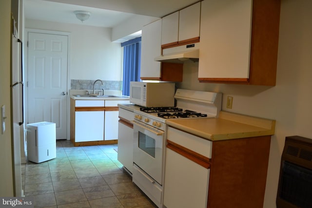 kitchen with white appliances, sink, white cabinetry, and light tile floors