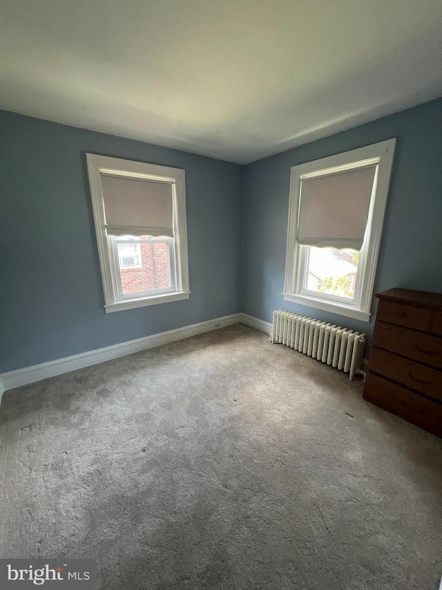 carpeted spare room featuring radiator