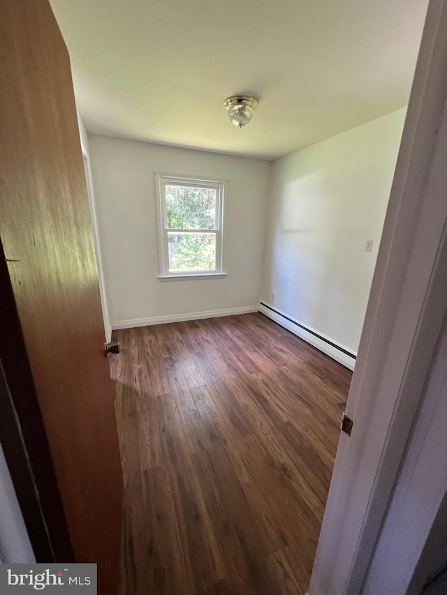 unfurnished room with dark hardwood / wood-style flooring and baseboard heating