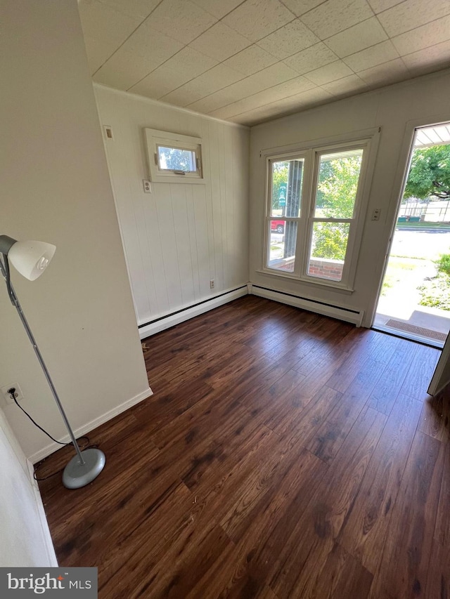 spare room with dark wood-type flooring and a baseboard radiator