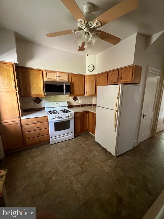 kitchen with white appliances, backsplash, ceiling fan, and dark tile flooring