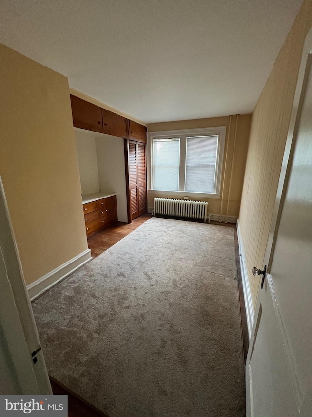 carpeted spare room featuring radiator