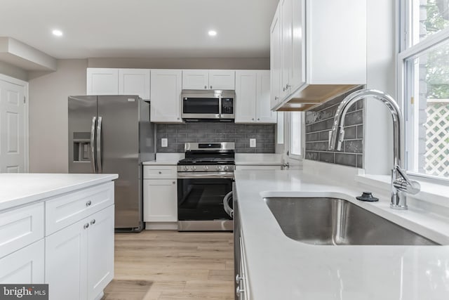 kitchen with light hardwood / wood-style flooring, tasteful backsplash, sink, white cabinetry, and appliances with stainless steel finishes