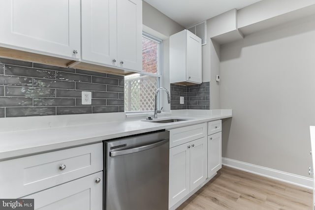 kitchen featuring light hardwood / wood-style flooring, stainless steel dishwasher, backsplash, sink, and white cabinetry