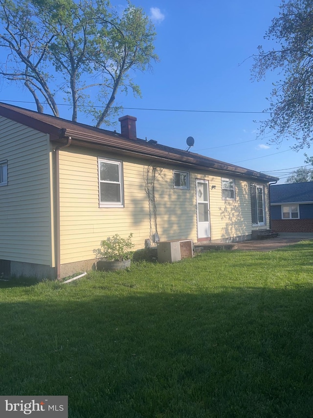 back of property featuring central air condition unit and a lawn