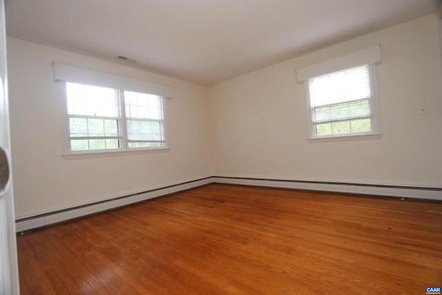 empty room featuring hardwood / wood-style floors and a baseboard heating unit