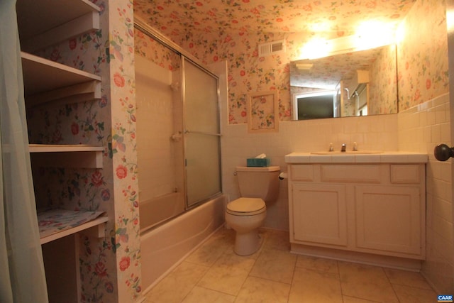 full bathroom featuring tile walls, shower / bath combination with glass door, vanity, tile patterned flooring, and toilet