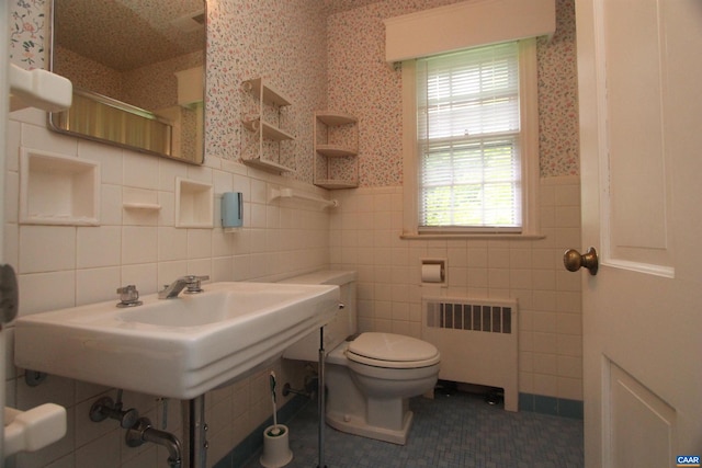 bathroom with radiator heating unit, tile walls, and toilet