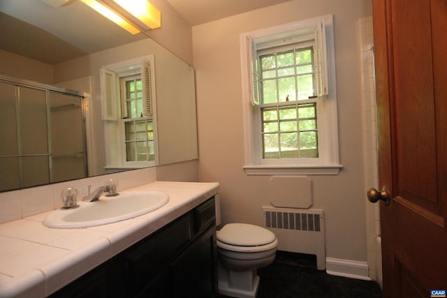 bathroom with radiator heating unit, tile patterned floors, toilet, vanity, and walk in shower