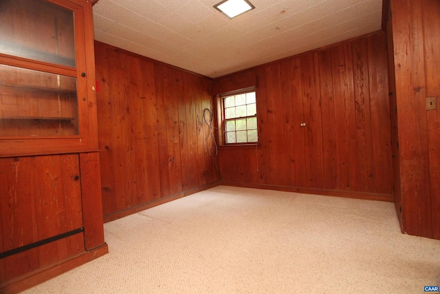 carpeted spare room featuring wooden walls