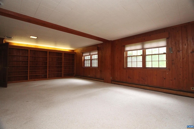 unfurnished room with light colored carpet, wooden walls, and a baseboard heating unit