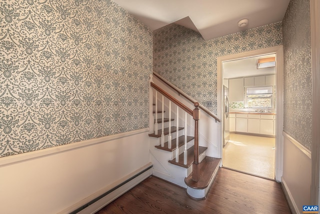 staircase with hardwood / wood-style floors, a baseboard radiator, and sink