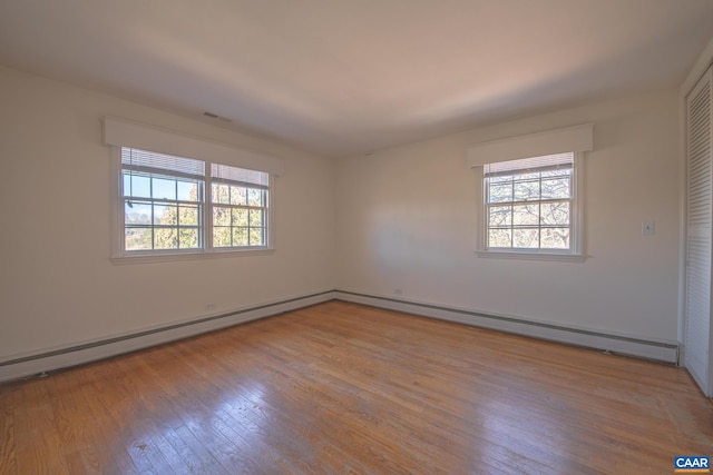 spare room with a baseboard heating unit and light wood-type flooring