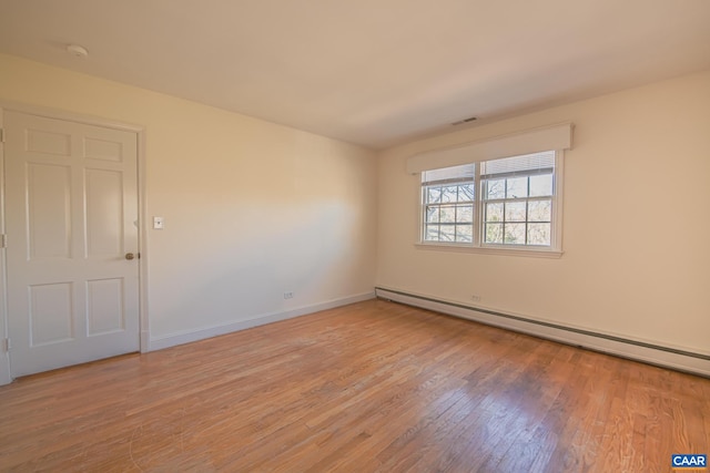 unfurnished room with baseboard heating and light hardwood / wood-style flooring