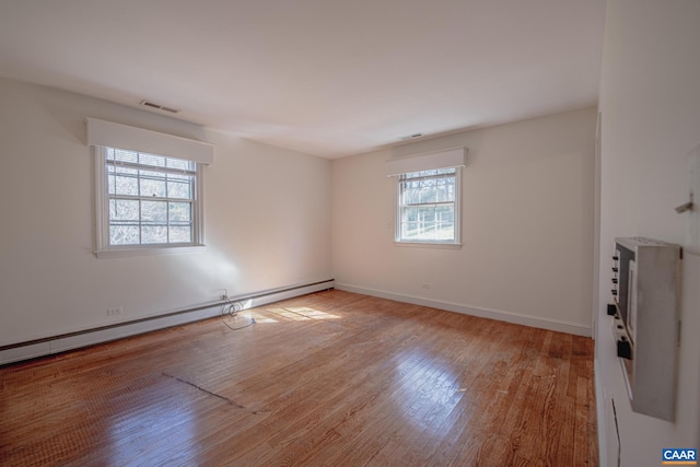 unfurnished room featuring baseboard heating and light hardwood / wood-style floors