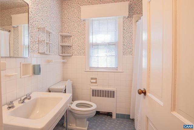 bathroom with tile walls, radiator heating unit, sink, and toilet