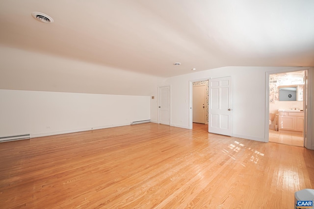 bonus room with a baseboard heating unit, light wood-type flooring, and vaulted ceiling