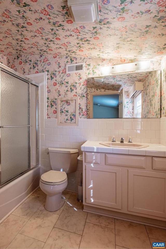 full bathroom with shower / bath combination with glass door, tile patterned floors, vanity, and toilet