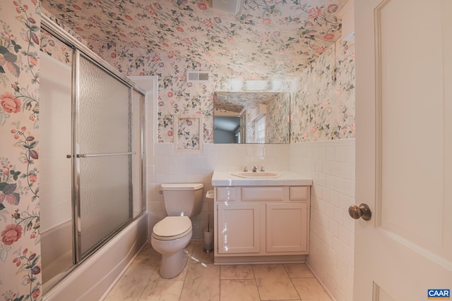 full bathroom with enclosed tub / shower combo, tile patterned floors, toilet, tile walls, and vanity