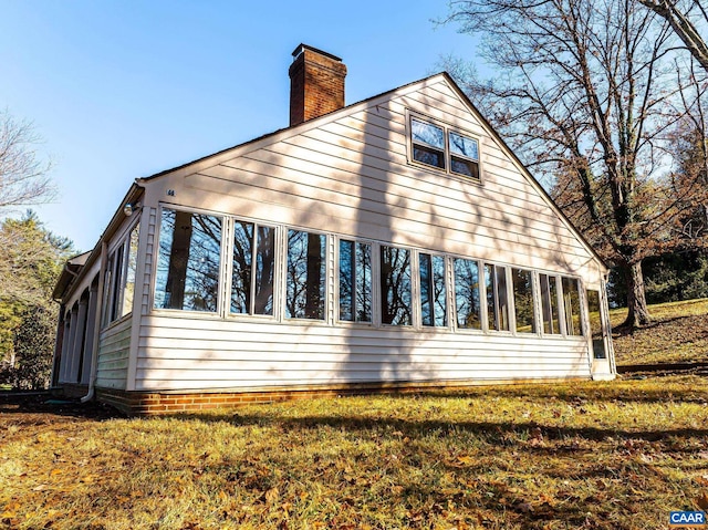 view of side of property featuring a sunroom and a lawn