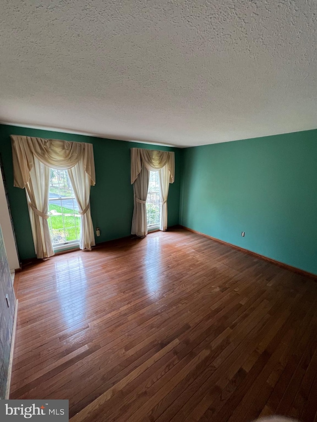 unfurnished room featuring a textured ceiling and dark hardwood / wood-style floors