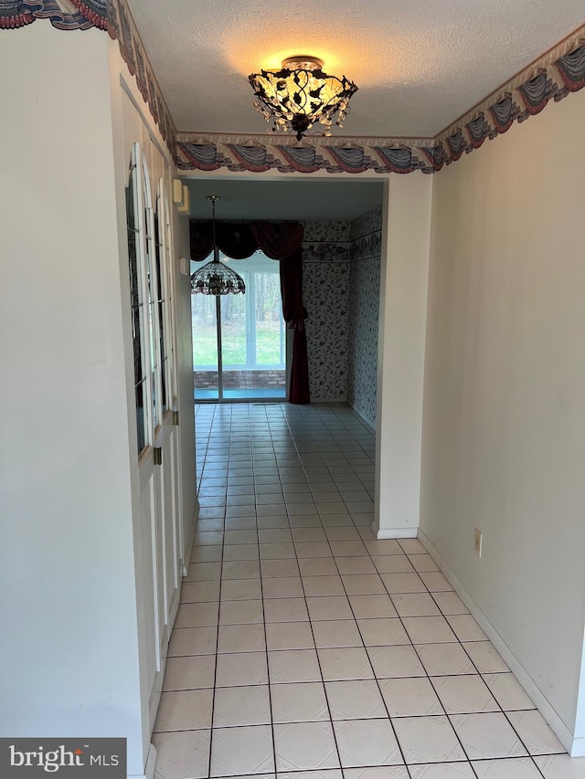 corridor with a textured ceiling and light tile flooring