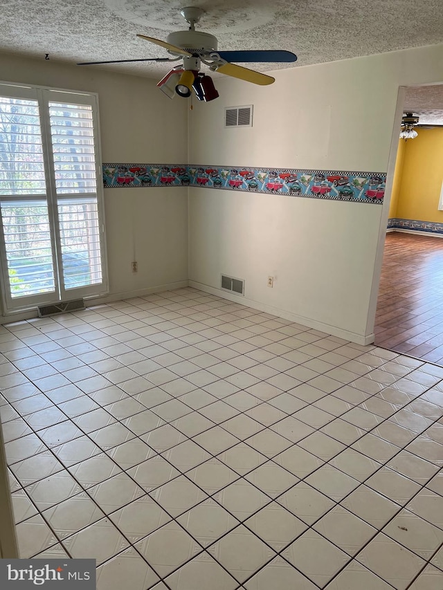 spare room with ceiling fan, a textured ceiling, and light tile flooring