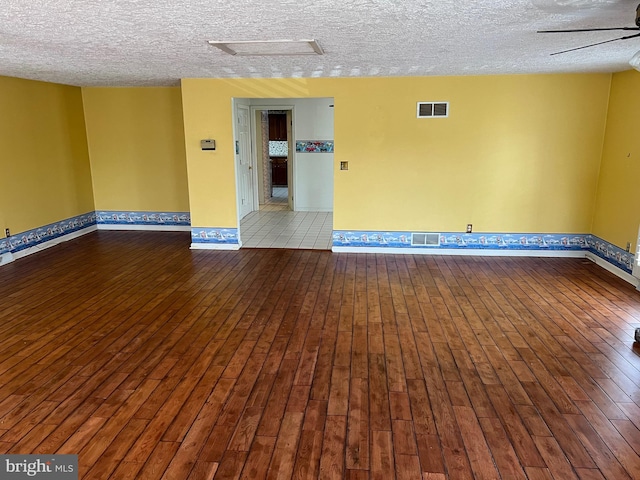 spare room with a textured ceiling, dark wood-type flooring, and ceiling fan