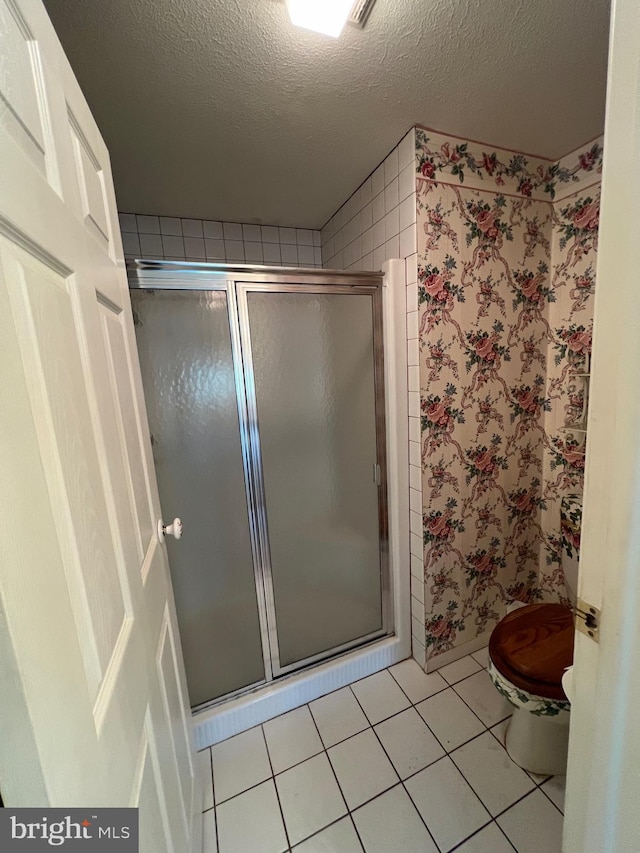 bathroom with tile floors, walk in shower, a textured ceiling, and toilet