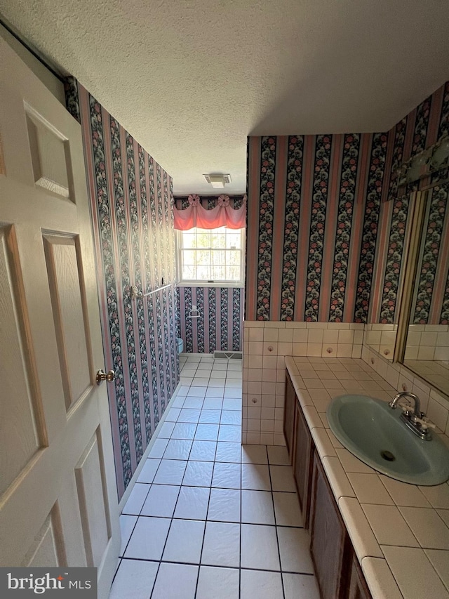 bathroom featuring tile floors, a textured ceiling, backsplash, and vanity