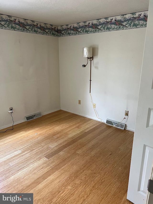 spare room with a textured ceiling and light wood-type flooring