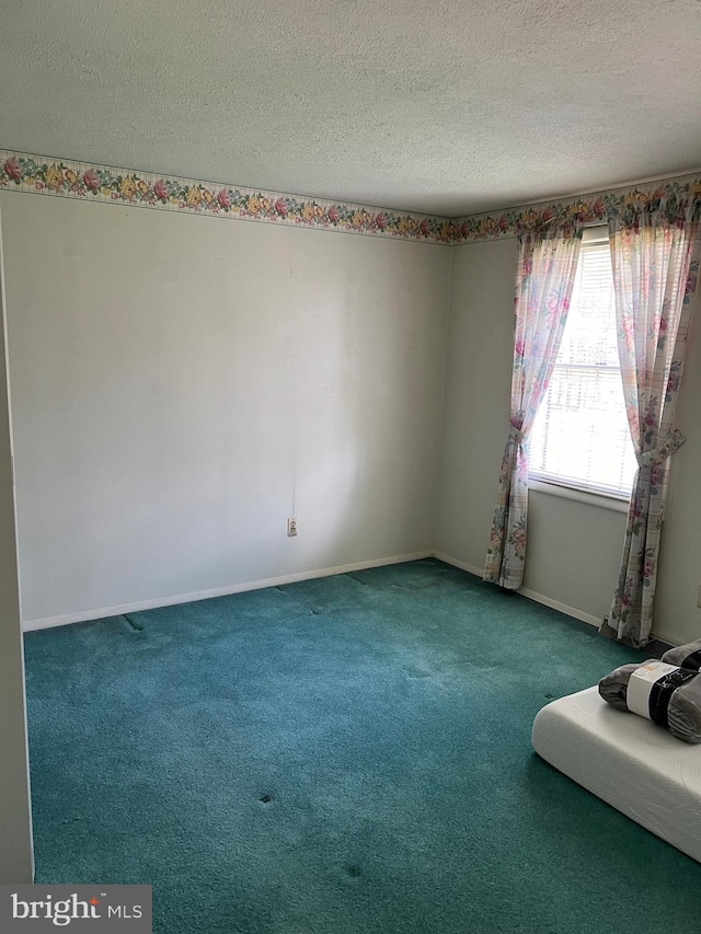 carpeted spare room with a textured ceiling