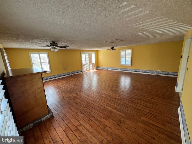 unfurnished room with ceiling fan, dark hardwood / wood-style flooring, and a textured ceiling