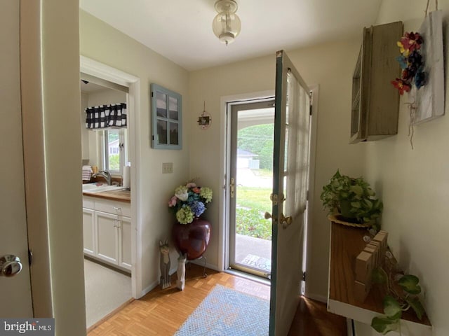 foyer entrance with light parquet flooring, sink, and a wealth of natural light